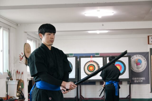 한 참가자가 진지한 표정으로 검을 잡고 '태극검세' 기본 자세를 취하고 있다. 태권도 품새의 절도와 검의 예리함이 조화를 이룬다.