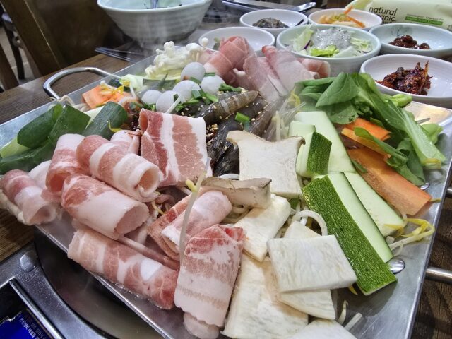 “철판 위에 핀 맛의 꽃” 행복낙지의 대표 메뉴인 낙지철판볶음. 선홍빛 대패 삼겹살과 통통한 새우, 메추리알, 그리고 신선한 각종 채소가 푸짐하게 담겨 시각적인 즐거움을 먼저 선사한다.