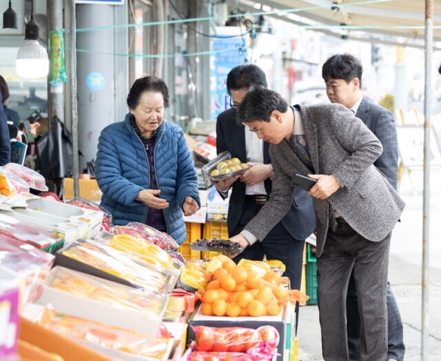 김돈곤 청양군수가 청양전통시장에서 과일을 고르며 농어촌 기본소득을 사용하는 모습(사진=청양군)