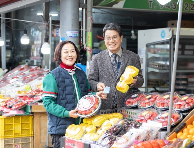 김돈곤 청양군수가 청양전통시장에서 과일을 고르며 농어촌 기본소득을 사용하는 모습(사진=청양군)
