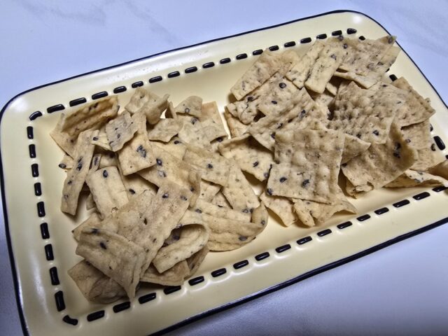 접시에 담긴 과자는 인위적인 광택 없이 담백한 질감을 보여준다. 검은깨가 콕콕 박혀 있어 고소함을 시각적으로 강조하며, 한입 크기로 정제된 형태가 돋보인다.