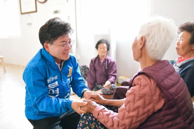 어르신의 손을 따뜻하게 맞잡고 건강과 안부를 물으며 노인 복지 인프라 확충에 대한 건의 사항을 경청하고 있다.