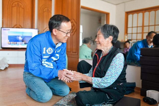 구 후보는 지역내 마을 노인정을 찾아 어르신 효도 공약을 내세우며 어르신의 하루를 따뜻하게 보낼 수 있도록 하겠다고 약속하며 밝게 웃고 있다。