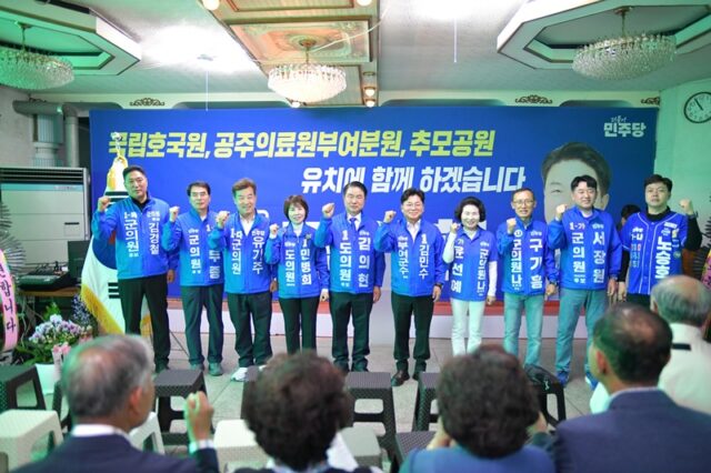 더불어민주당 소속 부여군 지방선거 후보자들이 단체로 단상에 올라 주먹을 맞쥐며 동반 승리를 다짐하고 있습니다.