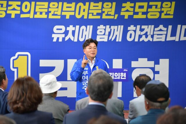 김민수 부여군수 후보가 선거사무소 개소식 연단에 올라 지지자들에게 열정적으로 지지를 호소하고 있습니다.