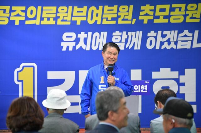 의현 도의원 후보가 마이크를 잡고 개소식을 찾아준 지역 주민과 지지자들에게 환한 미소로 인사말을 전하고 있습니다.