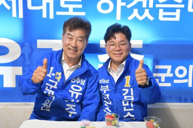 유기주 군의원 후보와 김민수 부여군수 후보가 나란히 앉아 엄지를 치켜세우며 동반 당선의 의지를 다지고 있습니다.