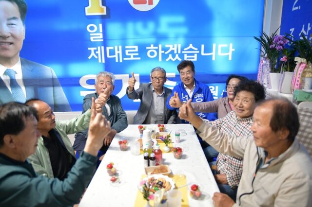 지역 어르신들과 함께 둘러앉아 엄지 포즈를 취하며 친근하게 소통하고 있는 유기주 후보.