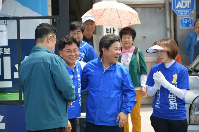 환한 미소로 서로의 어깨를 감싸며 파이팅을 외치는 박정현 전 군수와 김민수 후보.
