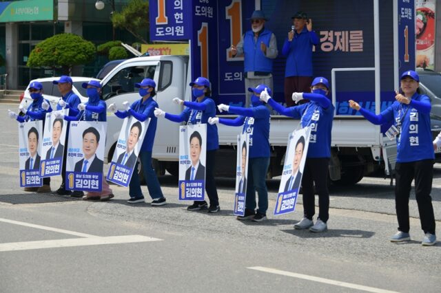 부여군 남면 서부여농협 앞에 마련된 집중 유세 현장에서 이기철 후원회장이 유세차 연단에 올라 마이크를 잡고 김의현 충남도의원 후보에 대한 지지를 호소하고 있다. 유세차 앞에는 선거운동원들이 일렬로 서서 힘을 보태고 있다.