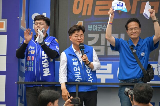 박주민 의원(오른쪽)이 홍보 피켓을 치켜들며 유권자들의 결집을 유도하는 가운데, 김민수 부여군수 후보(가운데)가 마이크를 잡고 ‘능력 있는 여당 후보론’을 외치며 지지 연설을 진행하고 있다.