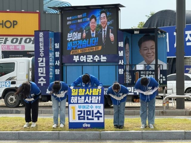 대형 LED 화면이 설치된 유세 차량 앞에서 부여 군민들을 향해 90도로 허리 숙여 정중히 절을 올리고 있는 김민수 후보와 자녀들. 13일 동안 길 위에서, 시장에서 만난 모든 유권자의 격려에 진심 어린 감사를 표하는 장면이다.