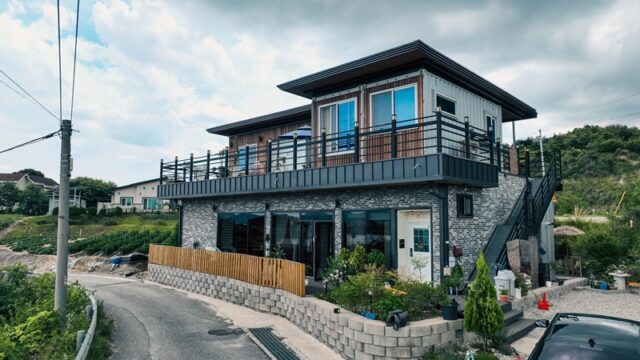 모던한 회색 벽돌과 상부 컨테이너 가옥 구조가 조화를 이룬 2층 건물