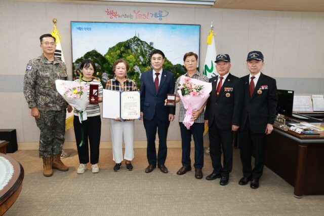 이응우 계룡시장이 21일 시청 시장 집무실에서 열린 '6·25전쟁 화랑무공훈장 전수식'에서 고(故) 민영구 하사의 유가족에게 화랑무공훈장을 전수한 뒤 참석자들과 기념촬영을 하고 있다.(사진=계룡시)